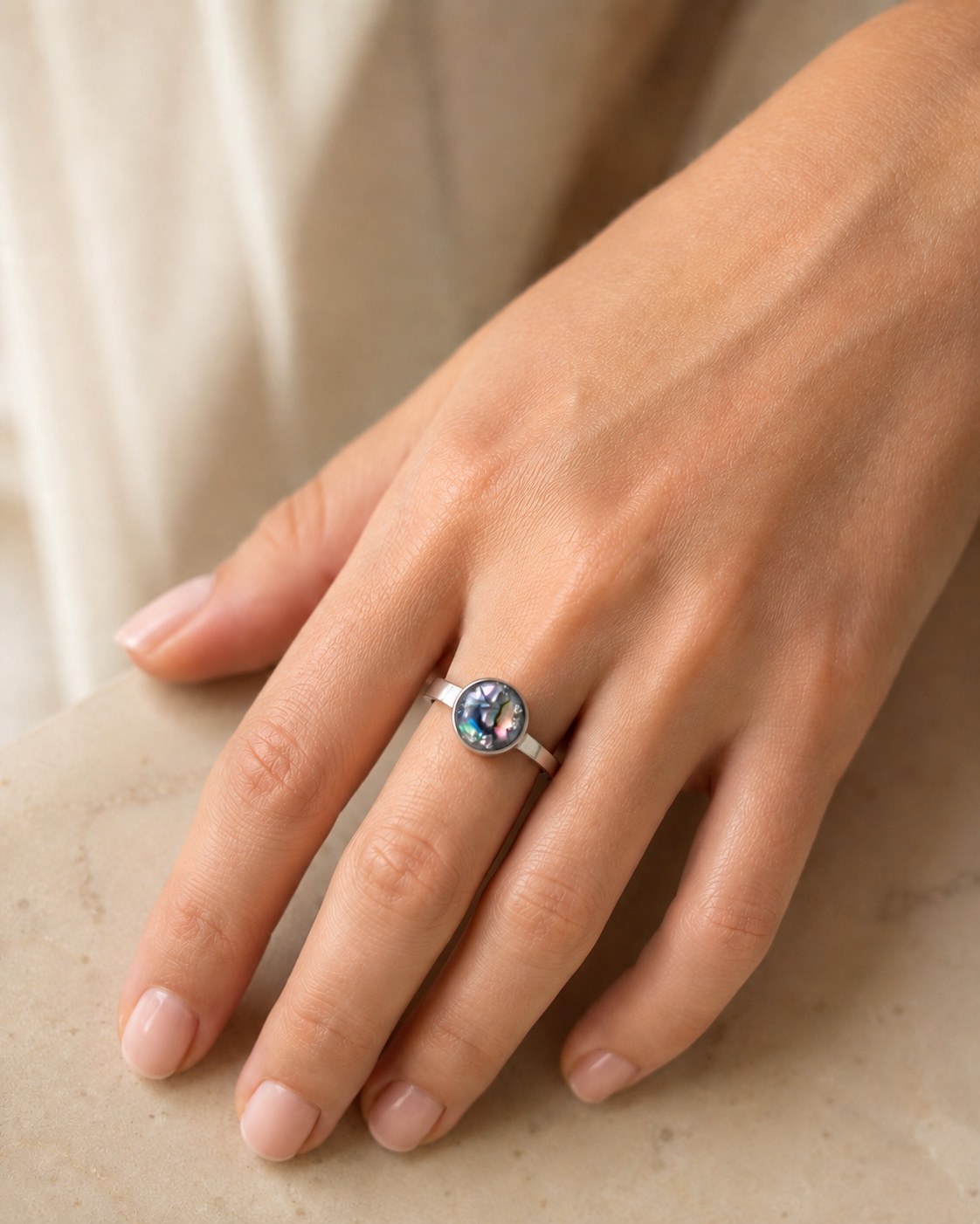 Iridescent round memorial ring worn on a hand