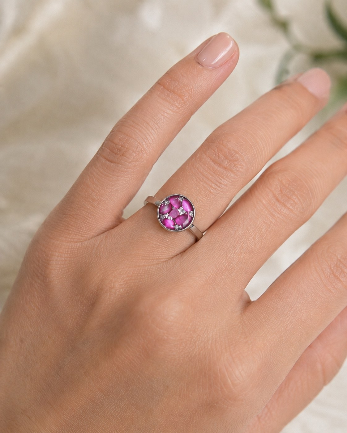 Pink round memorial ring worn on a hand